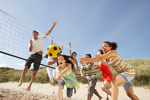 Group of friends playing volleyball on the beach stock photo