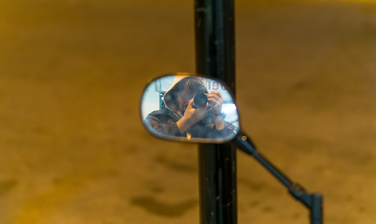 Necochea, Buenos Aires, Argentina. January 31, 2021. Photographer capturing himself in the small mirror of a motorcycle.