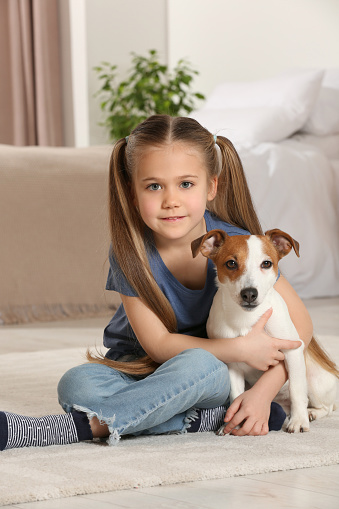 Cute girl with her dog on floor at home. Adorable pet