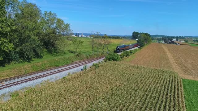 An Antique Steam Passenger Train, Approaching, Passing Thru Farmlands with Corn Fields, Waiting to be Harvested, on a Sunny Summer Day