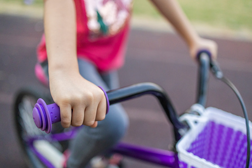 Close up photo of the girl who ride a bicycle. Bicycle and hand in the focus.