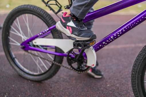Close up photo of the leg of a girl who holding on a bicycle pedal