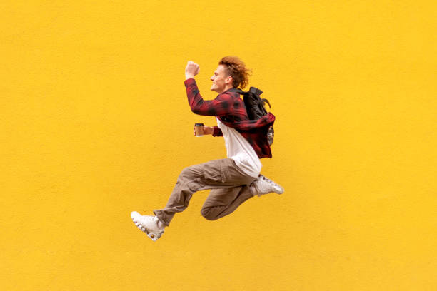 istock young cheerful guy student with backpack and coffee quickly runs in the air and jumps against the wall 1771417164