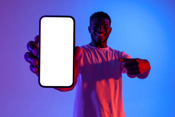 istock african american man showing empty smartphone screen in neon lighting, guy advertising copy space on phone 1771438326