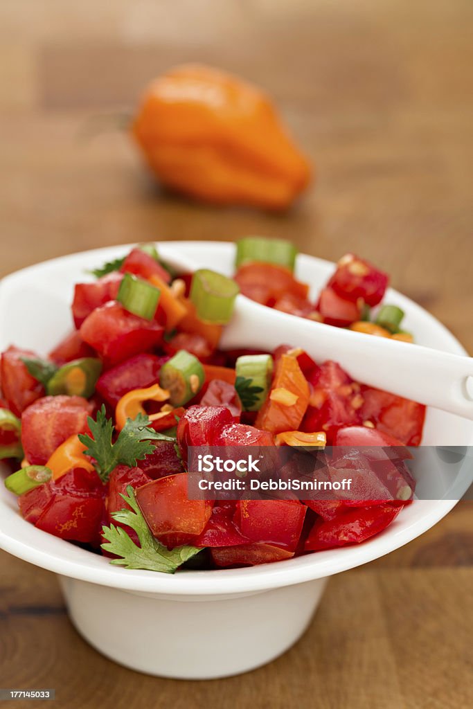 Habanero Salsa A close up shot of a small bowl full of hellishly spicy habanero salsa and a small soon. Bowl Stock Photo