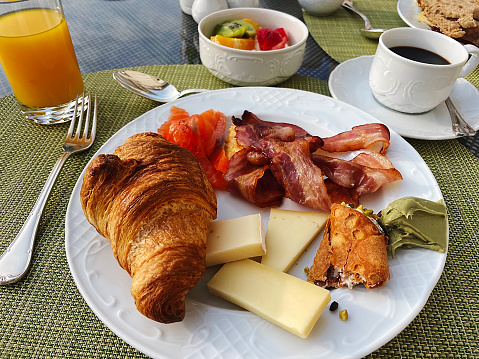 European style breakfast with croissant , cheese, bacon, coffee and orange juice.
