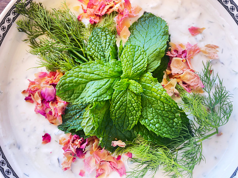A bowl of greek yoghurt dip decorated with fresh herbs, mint, dill,and rose petals!