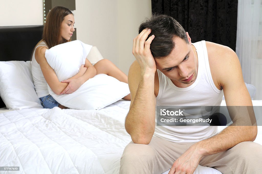 Sleeping Upset man having problem sitting on the bed with his girlfriend Erectile Dysfunction Stock Photo