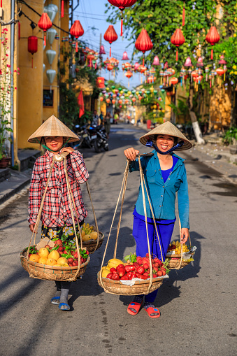 Vietnamese women selling tropical fruits, old town in Hoi An city, Vietnam. Hoi An is situated on the east coast of Vietnam. Its old town is a UNESCO World Heritage Site because of its historical buildings.