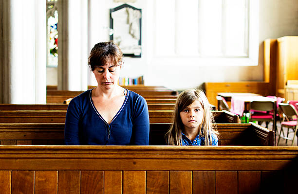 A mother and her young daughter sit in the pews in a church
