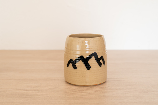 Handcrafted tumbler on a wooden table with pattern drawn