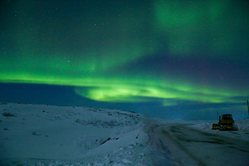 northern lights with green and purple glow in the starry sky and with track, horizontal, scenic