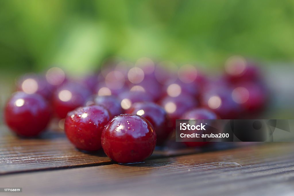 Scattered Cherry. wet cherry on a wooden plank on a green blurred background Alcohol - Drink Stock Photo