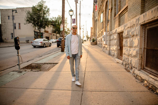 A young man, with a broad smile, looking at the camera while on a city street.