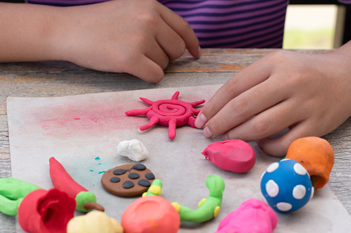 Children with learning disabilities are practicing plasticine shapes such as animals and fruits on the table with friends. Idea for learning by doing for children with learning disabilities.
