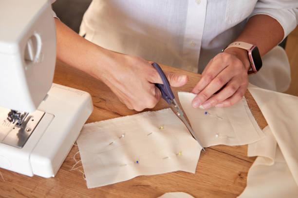 istock Seamstress cutting beige fabric with scissors. 1771597496