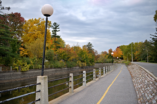 Bicycle lanes along Rideau canal in Ottawa used also as pedestrian walkway surrounded by forest landscape in autumn season in late October