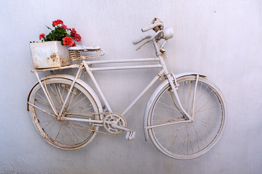 Old retro white bike attached to a white wall