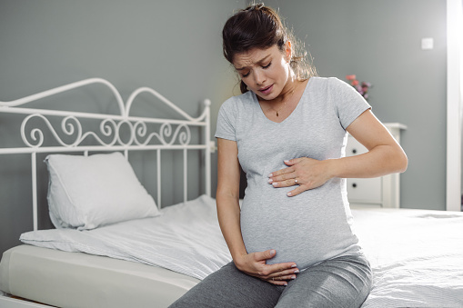 Beautiful pregnant woman having contraction at home, suffering from belly ache
