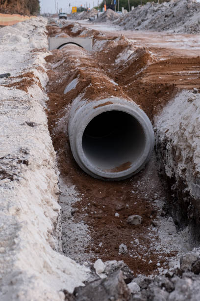 posa fognatura tubo di drenaggio in calcestruzzo tra grandi aree residenziali. nuova fognatura sanitaria, sistemi di scarico delle tempeste in cantiere. - bridge incomplete construction building activity foto e immagini stock