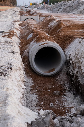 Laying sewer Concrete drainage pipe between large residential areas. New sanitary sewer, storm drain systems on construction site.