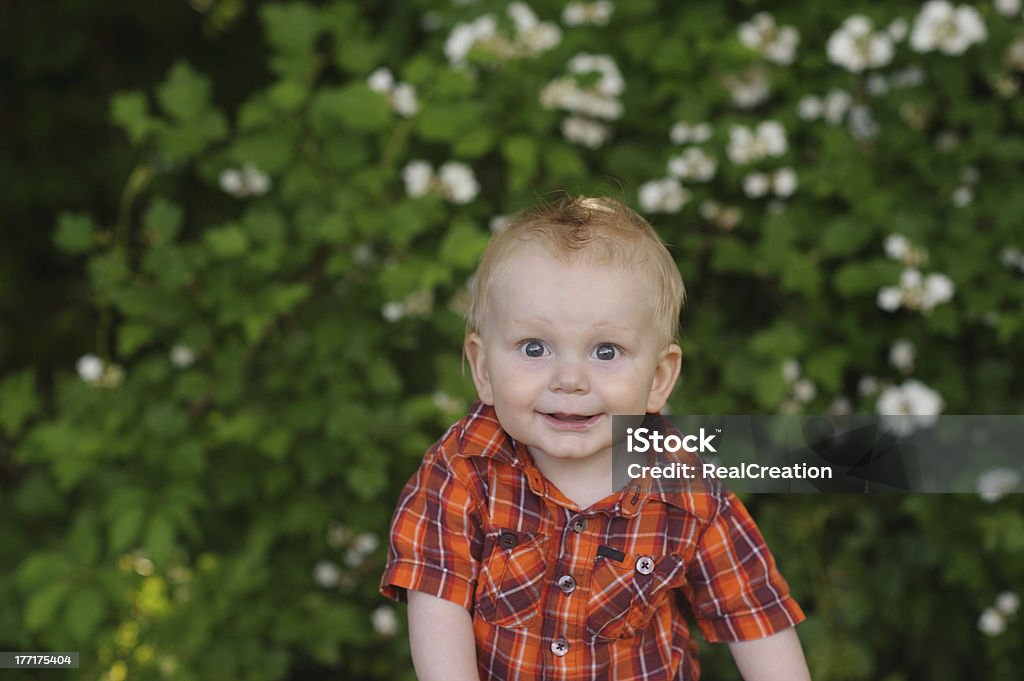 Bébé heureux assis à l'extérieur en face de fleurs - Photo de 12-23 mois libre de droits
