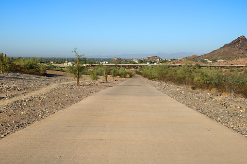 Dreamy Draw preserve dirt hiking trails and paved bike path near Arizona State Route 51 highway with a distant view of Phoenix downtown
