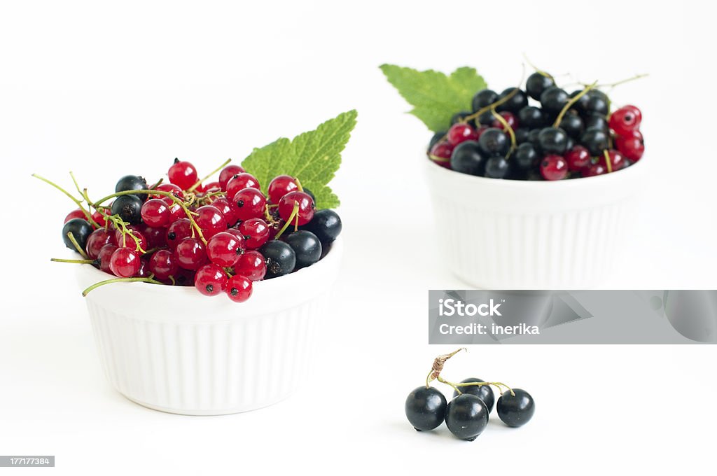 summer berries Two bowls with delicious black and red currants over white, selective focus Berry Fruit Stock Photo