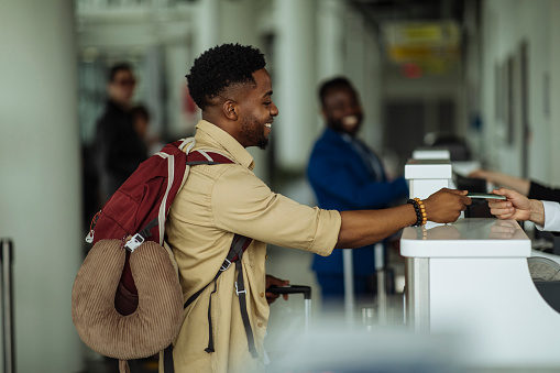 Side view of a young man standing in front of the airport counter