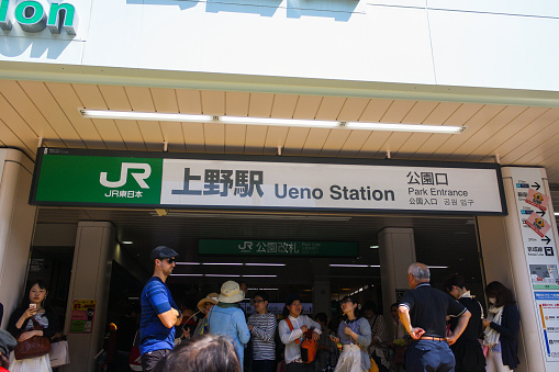 Tokyo, Japan - May 2014: View of JR Ueno Park station entrance with signage and crowd of people standing.