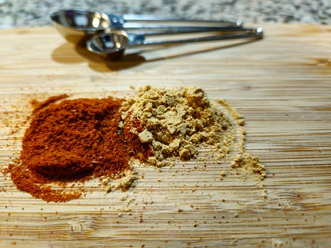 Spices And Measuring Spoons Sitting On Cutting Board