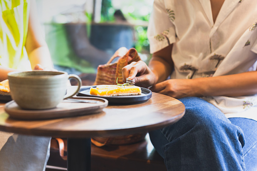 Woman eating lemom pie tart cake with coffee on table