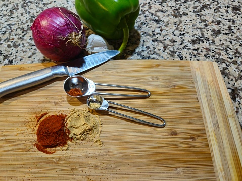 Spices, Vegetables And Cooking Utensils Sitting On Cutting Board