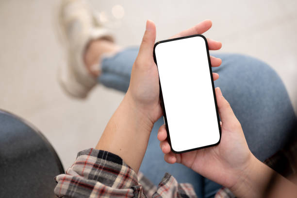 istock A woman using her smartphone while sitting indoors. A smartphone blank screen mockup 1771848202