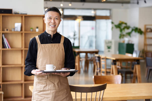 male employee of a restaurant standing inside the store - café edifício de restauração imagens e fotografias de stock