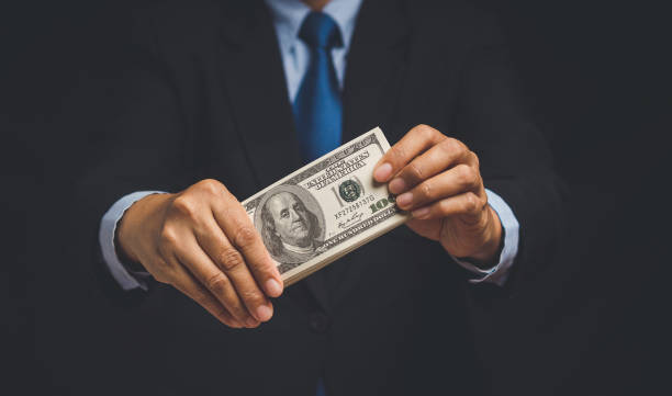 istock Businessman holding US dollar bills while standing on a black background 1771940436