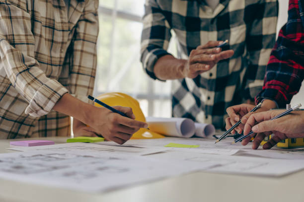 istock Engineer and businessman discussing construction project in office, team of engineers reviewing construction blueprints on new project with engineering tools at table in office 1771964733