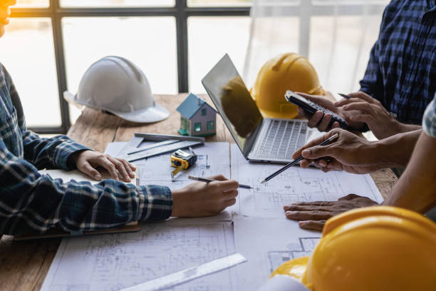 istock Engineer and businessman discussing construction project in office, team of engineers reviewing construction blueprints on new project with engineering tools at table in office 1771964767