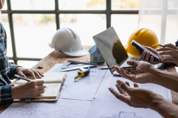 istock Engineer and businessman discussing construction project in office, team of engineers reviewing construction blueprints on new project with engineering tools at table in office 1771964775