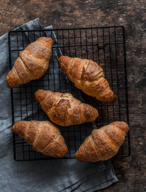 istock Fresh crispy croissants on a baking rack on a wooden background 1771982059