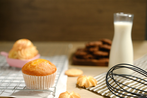 homemade muffins in white paper muffin cups and a glass of milk on the table..