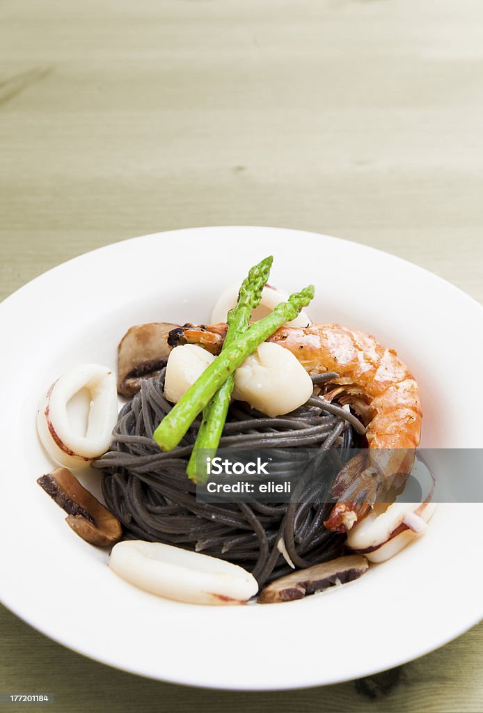 Nero spaghetti con frutti di mare sul tavolo di legno (pasta di Inchiostro di calamaro) - Foto stock royalty-free di Alimentazione sana
