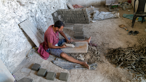 Fes, Morocco - 10 September 2022: Moroccan craftsman cutting tiles into a perfect square. These tiles are created with a mold, filled with a mixture of cement, sand, and pigment.