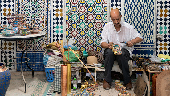 Fes, Morocco - 10 September 2022: Moroccan craftsman working with ceramics in a craft workshop to create pots, later to be displayed outside shops in the souks, or traditional markets.