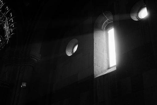 A grayscale of sunlight streams through a window in a church