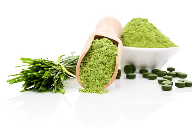 Healthy living. Spirulina; chlorella and wheatgrass. Green food supplement. Green pills; wheatgrass blades and ground powder isolated on white background. Healthy lifestyle. chlorella stock pictures, royalty-free photos & images