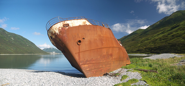 Shipwreck site in small bay, Old rusty whaling ship on the shore, bow view, Kamchatka, Morzhovaya bay