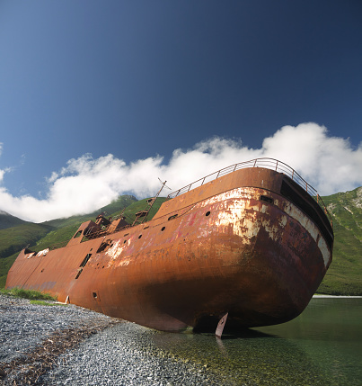 Shipwreck site in small bay, Old rusty whaling ship on the shore, stern view, Kamchatka, Morzhovaya bay