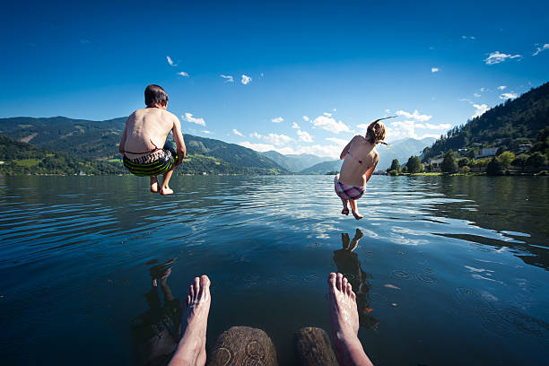 istock kids jumping into blue lake on summer day 177210286