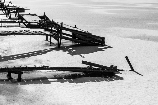 Fishing wooden bridges frozen and covered with snow on the icy surface of the lake.